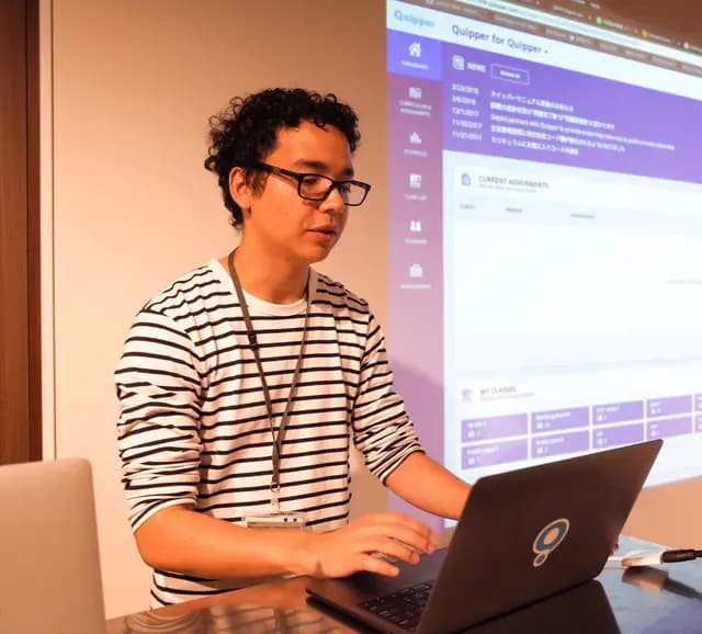 Davi on a stage making a presentation using a laptop